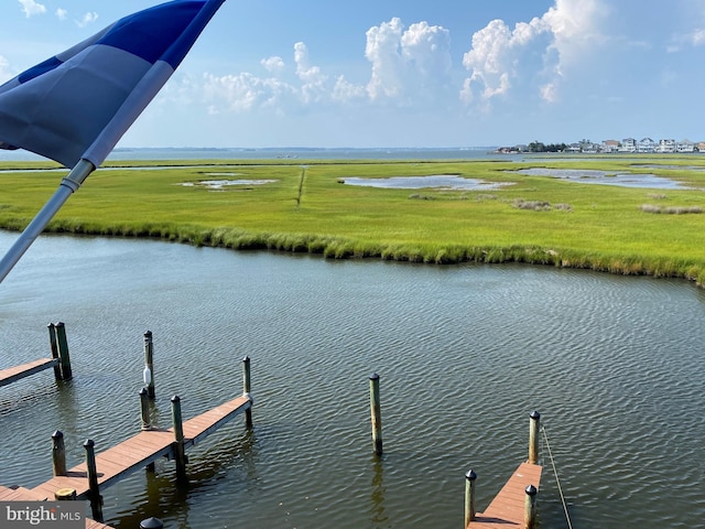 view of dock featuring a water view and a yard