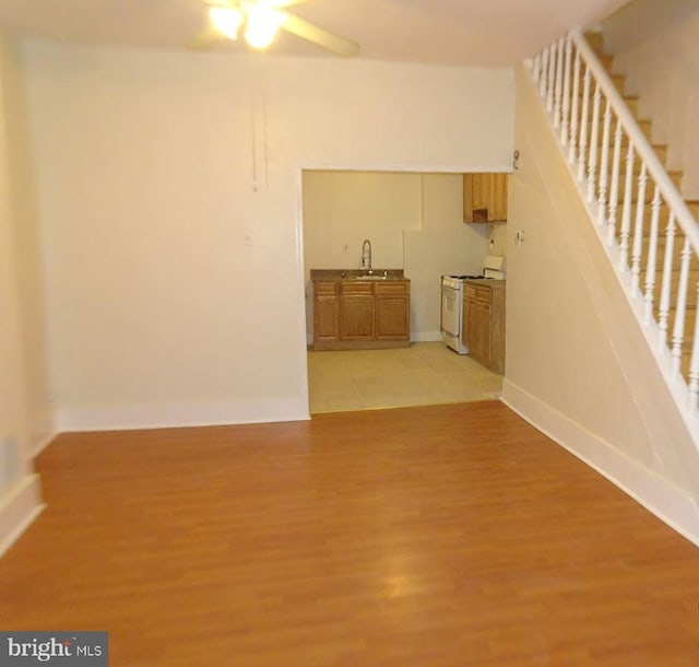 interior space featuring stairway, light wood-type flooring, a sink, and baseboards