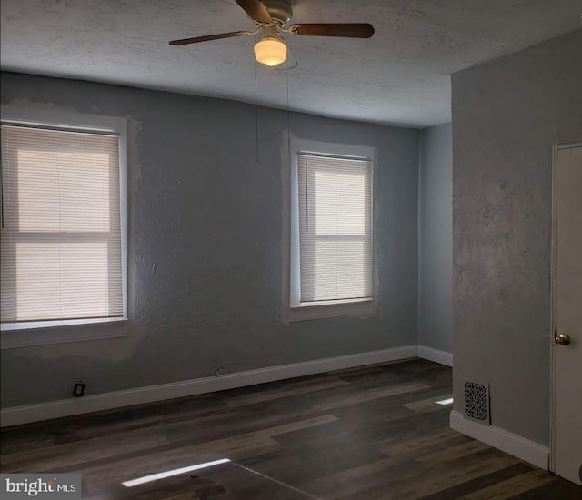 empty room with ceiling fan, a textured ceiling, wood finished floors, visible vents, and baseboards