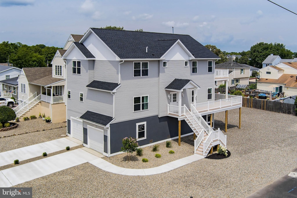 view of front of house with a shingled roof, fence, driveway, stairway, and a residential view