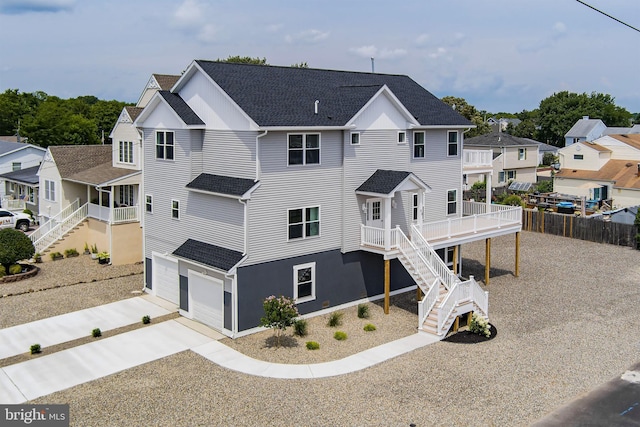 view of front of house with a shingled roof, fence, driveway, stairway, and a residential view