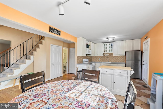 dining room featuring baseboards, stairway, and track lighting