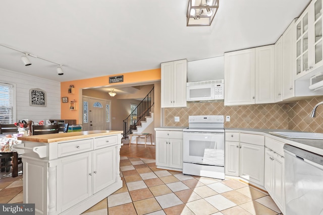 kitchen featuring white appliances, a sink, light countertops, white cabinetry, and backsplash