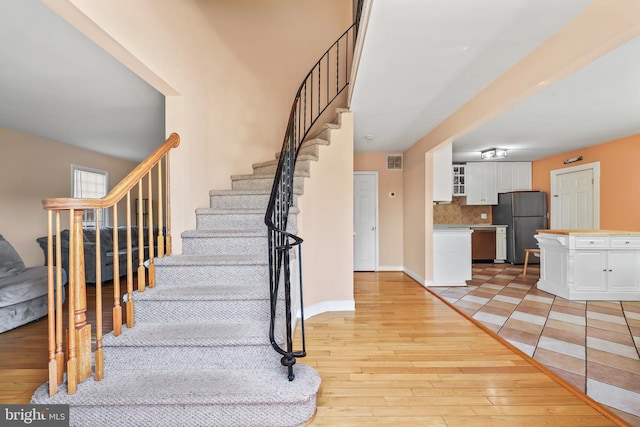 foyer featuring visible vents, stairs, light wood-style flooring, and baseboards