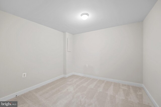 spare room with light carpet and baseboards