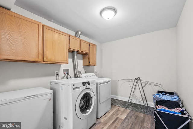 laundry area with cabinet space, light wood-style flooring, baseboards, and separate washer and dryer