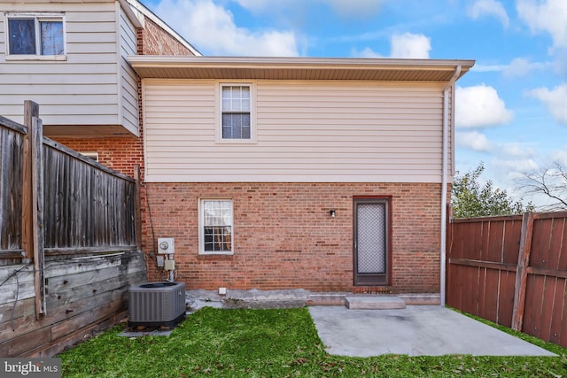 back of house with central AC, brick siding, a patio area, and a fenced backyard