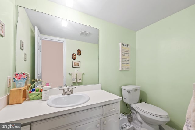 bathroom with toilet, vanity, and visible vents