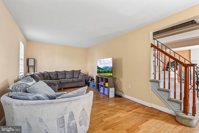 living room featuring light wood finished floors, stairs, and baseboards