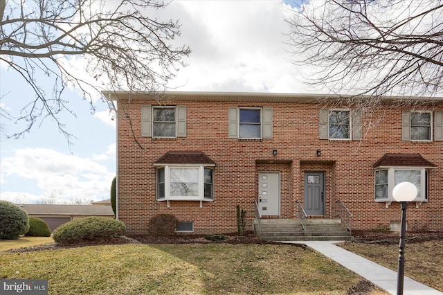 view of front facade with brick siding and a front yard