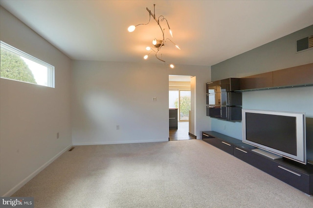 unfurnished living room featuring plenty of natural light, carpet flooring, visible vents, and baseboards