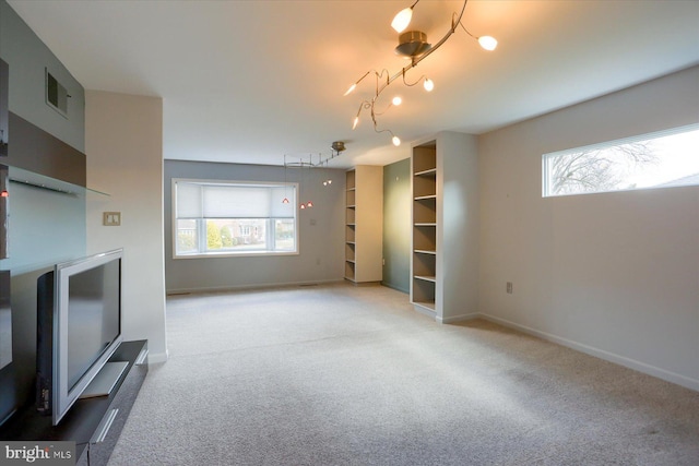 unfurnished living room featuring carpet floors, a healthy amount of sunlight, baseboards, and visible vents