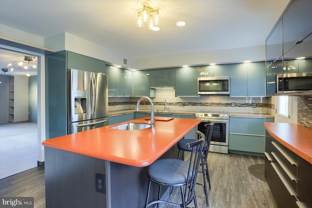 kitchen featuring dark wood-style floors, modern cabinets, appliances with stainless steel finishes, a sink, and backsplash