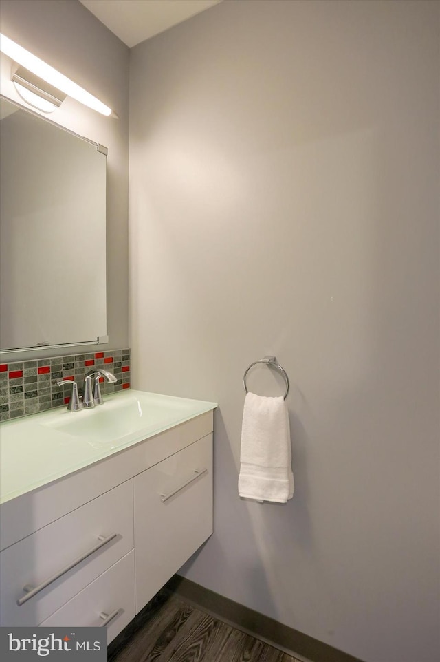 bathroom with wood finished floors, backsplash, and vanity