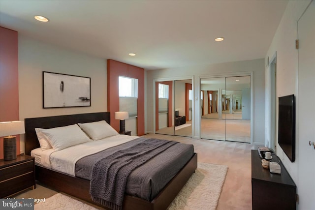 bedroom featuring recessed lighting, two closets, and light colored carpet