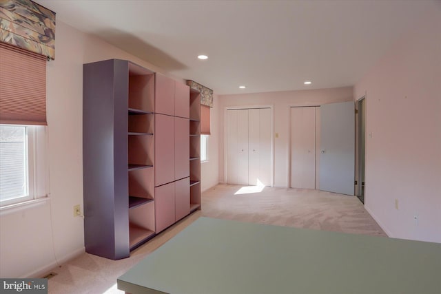 unfurnished bedroom with light carpet, visible vents, two closets, and recessed lighting