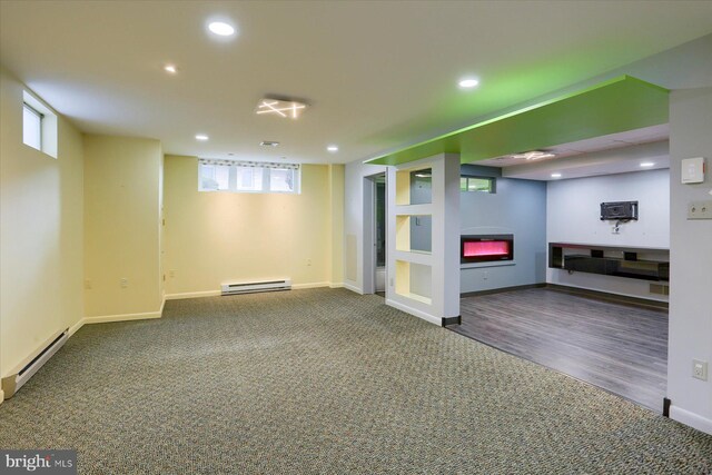 basement with a baseboard radiator, recessed lighting, baseboards, baseboard heating, and a glass covered fireplace