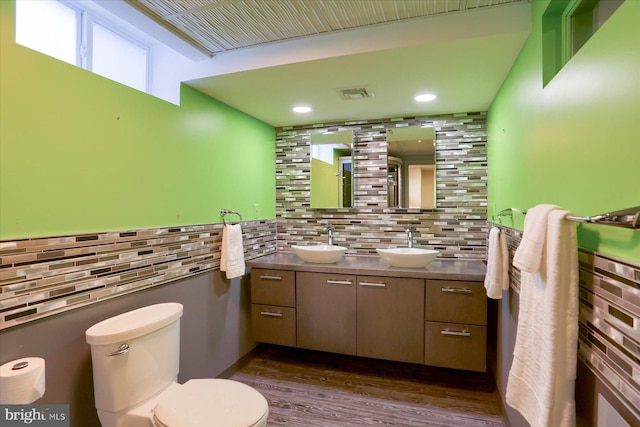 bathroom with toilet, double vanity, a sink, and wood finished floors