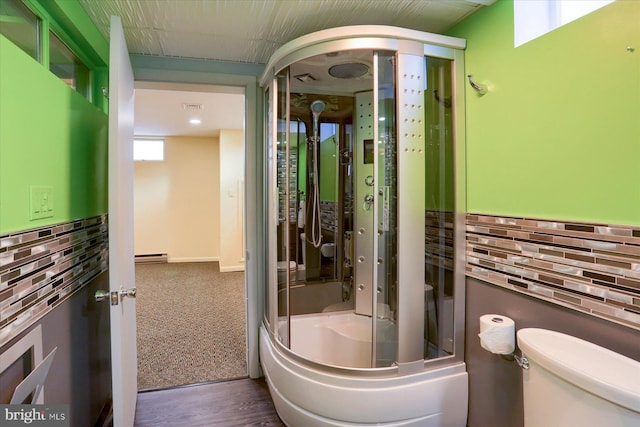 full bath with a baseboard heating unit, backsplash, toilet, and a shower with door