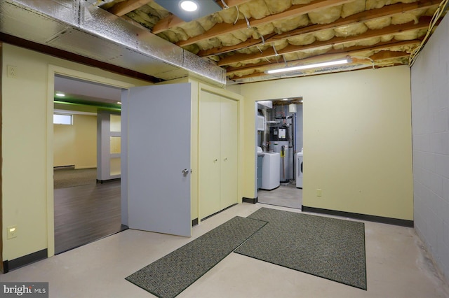 unfinished below grade area with concrete block wall and washer and clothes dryer