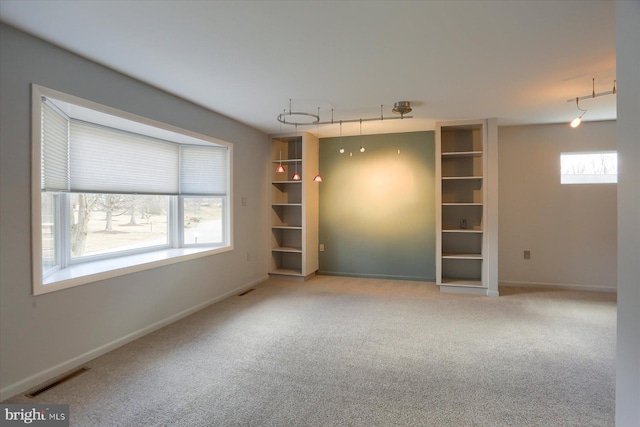 unfurnished room featuring carpet floors, rail lighting, visible vents, and baseboards