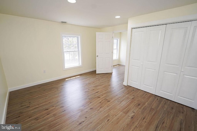 unfurnished bedroom featuring recessed lighting, dark wood-type flooring, visible vents, baseboards, and a closet