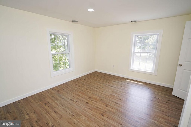 empty room featuring dark wood-style floors, visible vents, baseboards, and recessed lighting