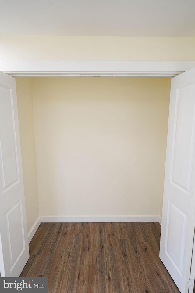 spare room featuring dark wood-style flooring and baseboards