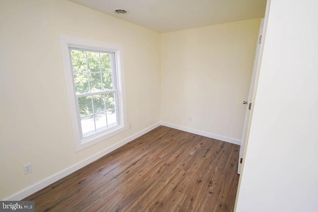 unfurnished room featuring visible vents, baseboards, and wood finished floors