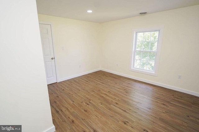 spare room featuring recessed lighting, dark wood finished floors, visible vents, and baseboards