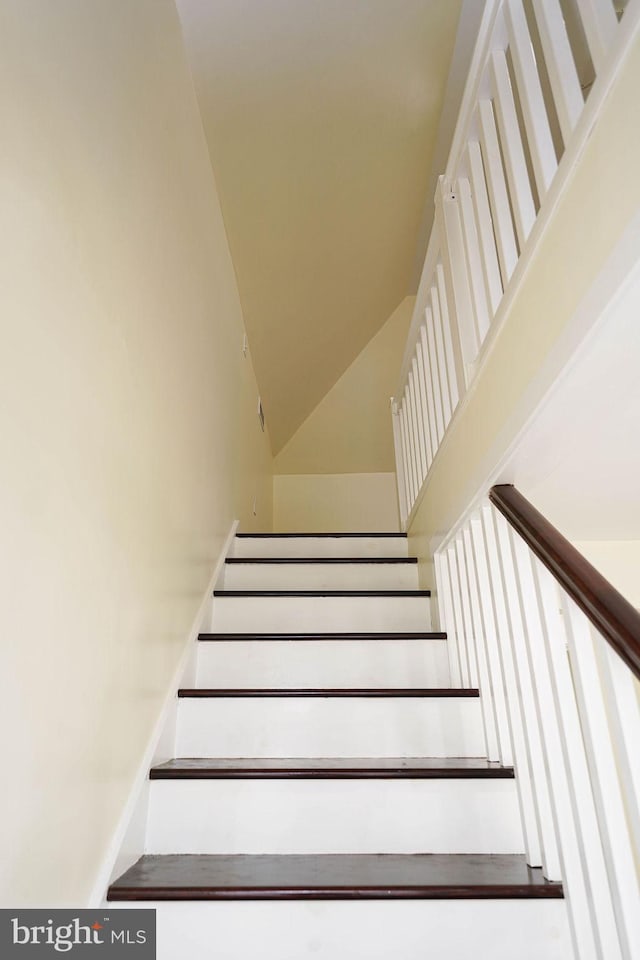 staircase featuring a high ceiling and baseboards