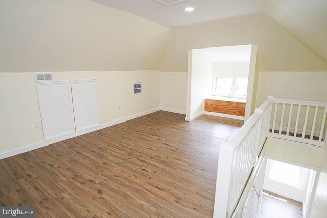 bonus room featuring visible vents, vaulted ceiling, baseboards, and wood finished floors