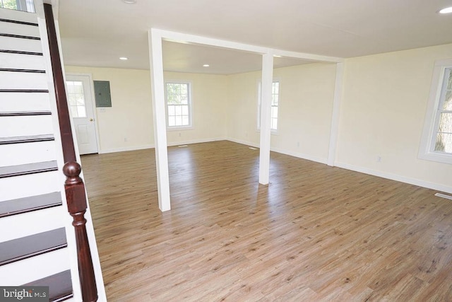 spare room with stairs, light wood finished floors, and electric panel