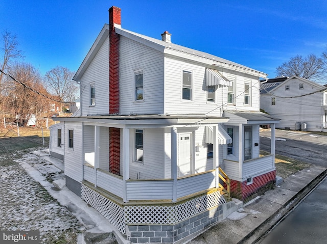 view of front facade featuring covered porch and a chimney