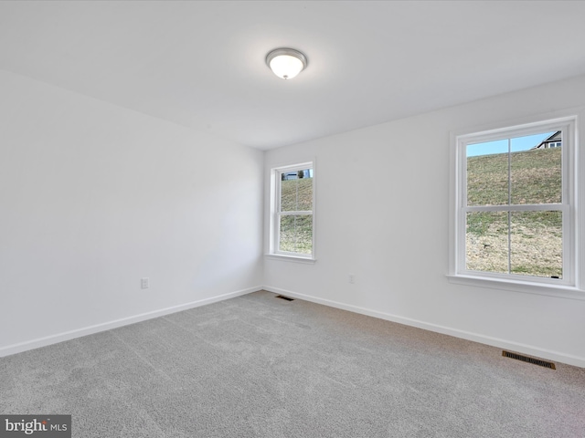 spare room with carpet floors, visible vents, and baseboards