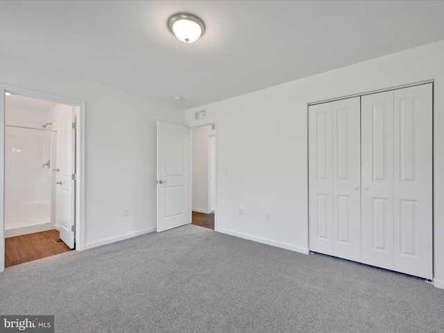 unfurnished bedroom with carpet, a closet, baseboards, and ensuite bathroom