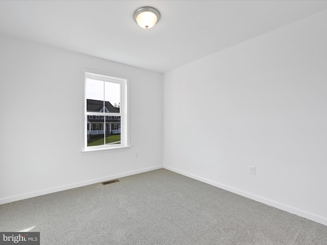 carpeted spare room with visible vents and baseboards