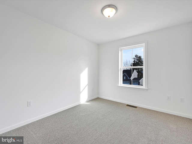 empty room with carpet floors, visible vents, and baseboards