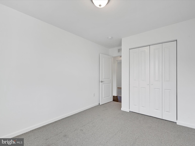 unfurnished bedroom featuring baseboards, a closet, and light colored carpet