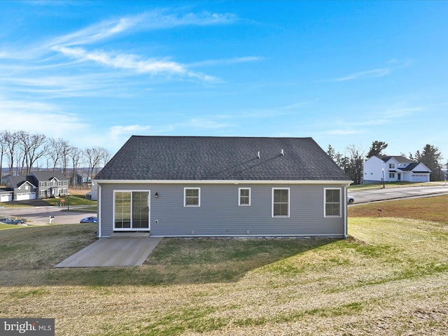 back of property with roof with shingles, a residential view, a lawn, and a patio