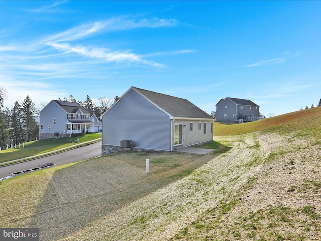 view of property exterior with central AC, a residential view, and a lawn