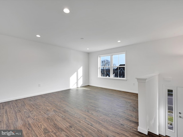 unfurnished living room with dark wood-type flooring, recessed lighting, and baseboards