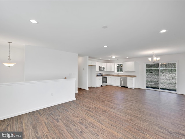 unfurnished living room featuring an inviting chandelier, baseboards, dark wood finished floors, and recessed lighting