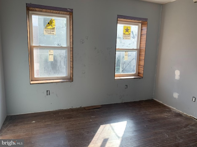 empty room with dark wood-style flooring and plenty of natural light