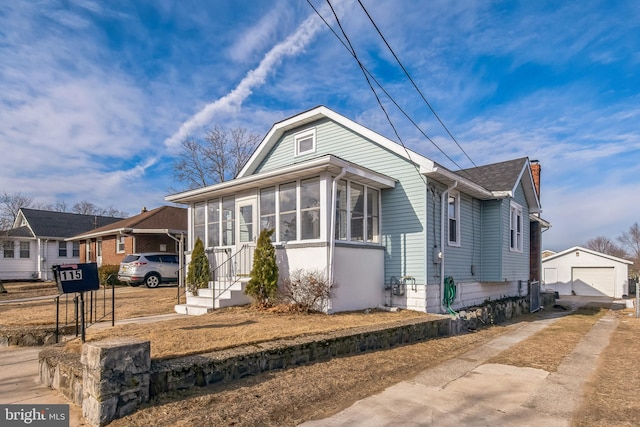 view of front of property with an outbuilding, a sunroom, a detached garage, and concrete driveway