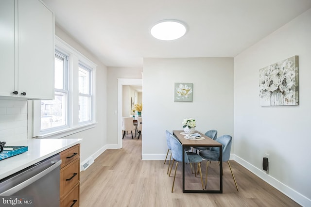 dining area with light wood-style floors, visible vents, and baseboards