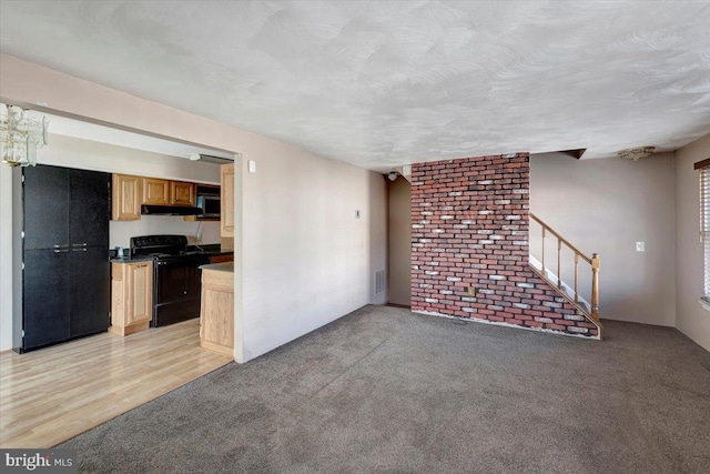 unfurnished living room with visible vents, light colored carpet, stairway, and a textured ceiling