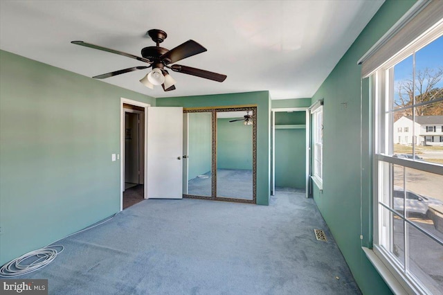 unfurnished bedroom featuring visible vents, carpet, and a ceiling fan