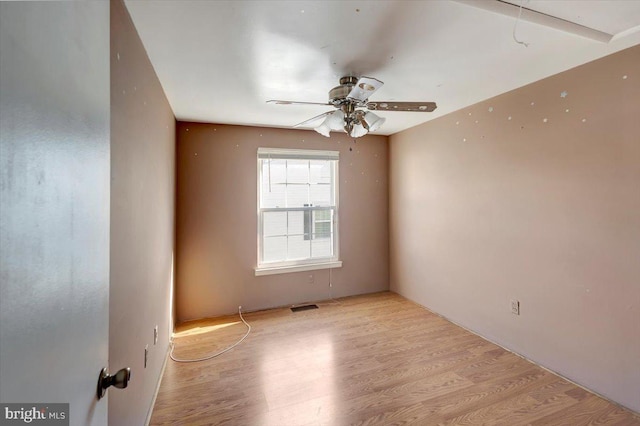 empty room with light wood-style floors, visible vents, and ceiling fan