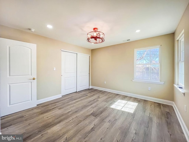 unfurnished bedroom with a closet, visible vents, light wood-style flooring, and baseboards